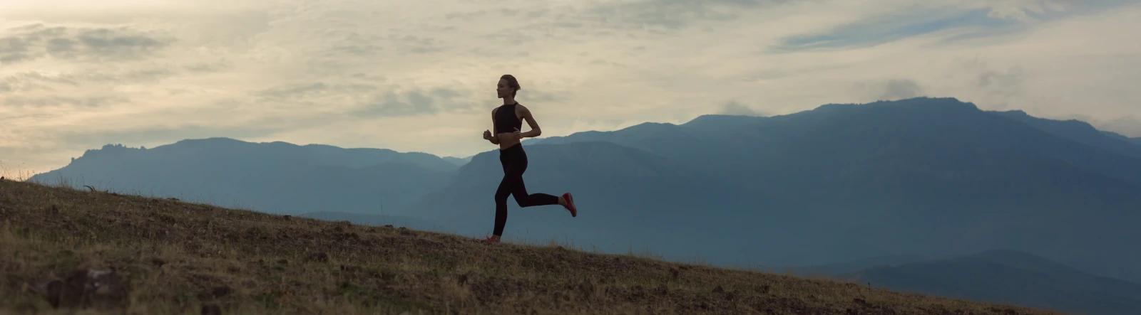a woman running up a grassy hill
