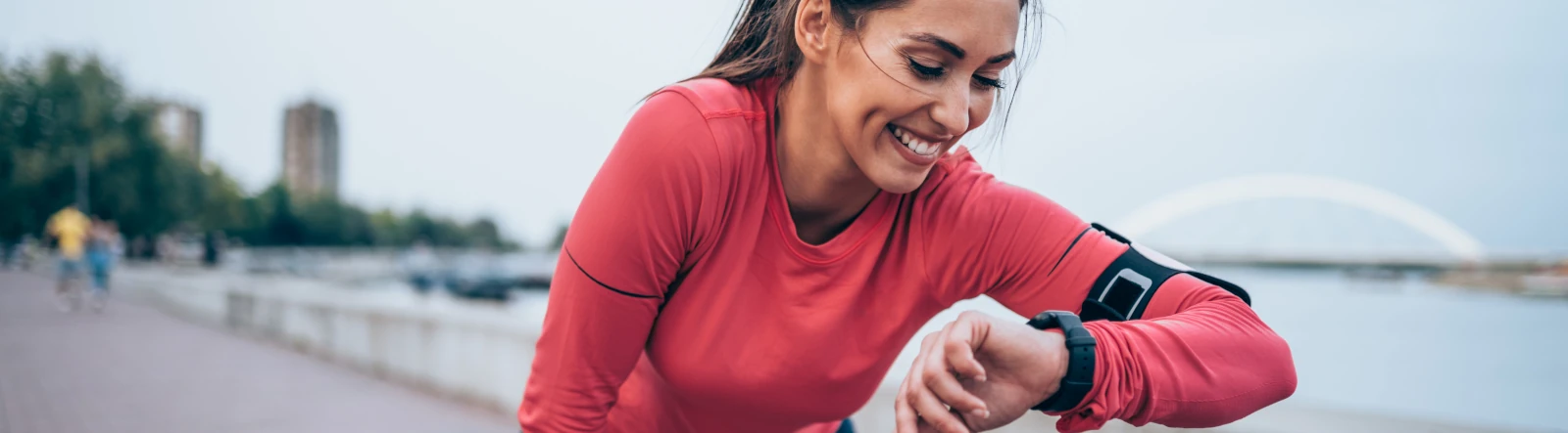 A woman looking at her runnning watch and smiling