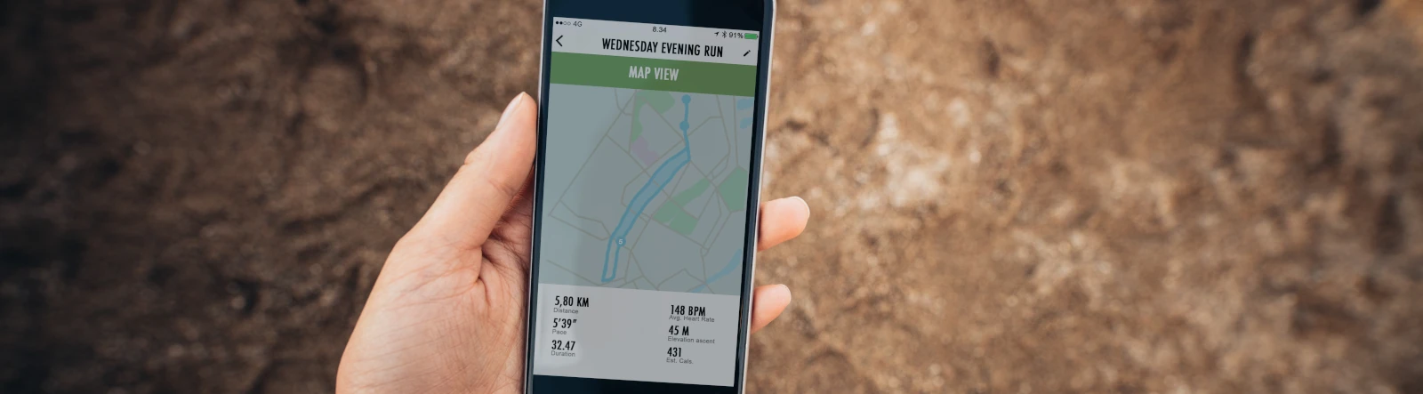 A hand holding a smartphone that is displaying a run map