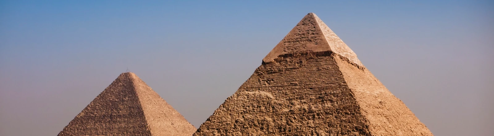 2 pyramids with blue sky in the background