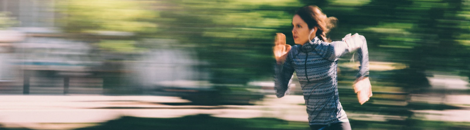 A woman running at speed with a motion-blurred background